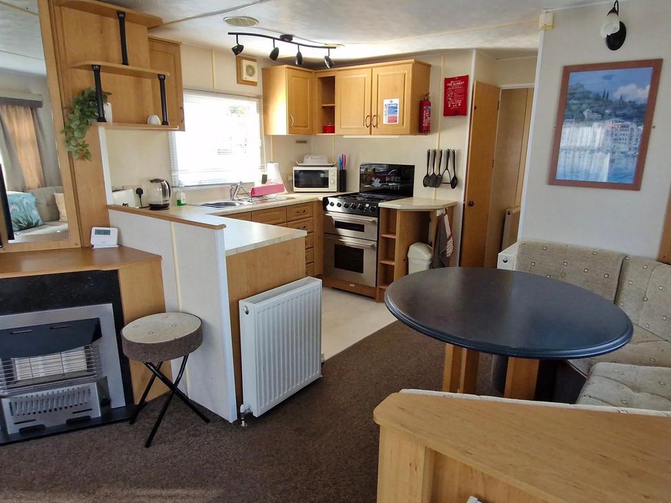 A kitchen area with appliances and a dining table at Woodland View Dog Friendly Nr Sutton on Sea in Thurlby near Alford