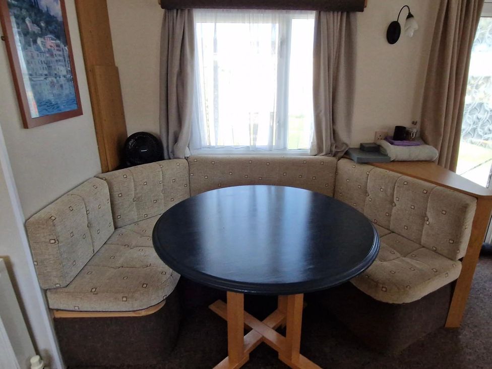 A dining area with a round table and seating at Woodland View Dog Friendly Nr Sutton on Sea, Thurlby near Alford