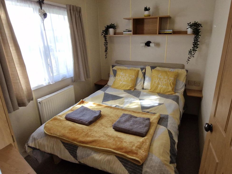 A bedroom with a bed and shelves at Woodland View Dog Friendly Nr Sutton on Sea in Thurlby near Alford