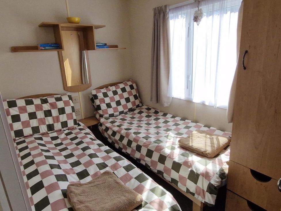 A bedroom with two beds and a shelf at Woodland View Dog Friendly Nr Sutton on Sea Thurlby near Alford