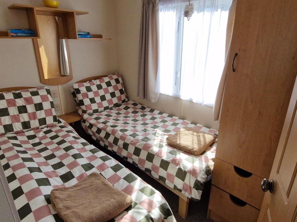 A bedroom with twin beds and a wardrobe at Woodland View Dog Friendly Nr Sutton on Sea Thurlby near Alford
