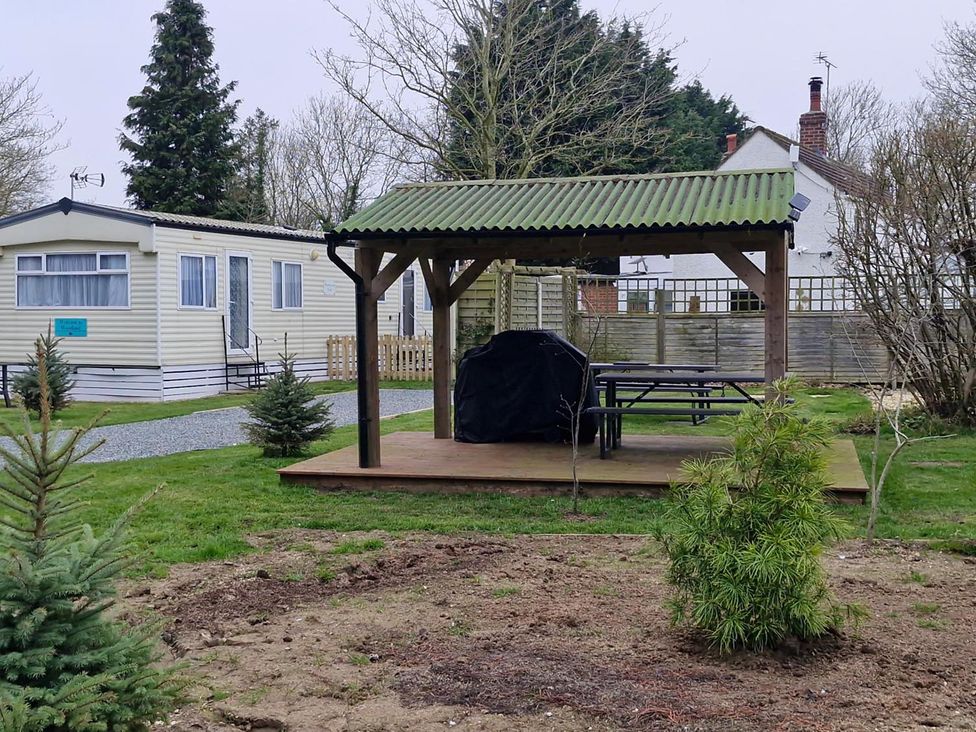 An outdoor area with a gazebo, table, and mobile home at Woodland View Dog Friendly Nr Sutton on Sea