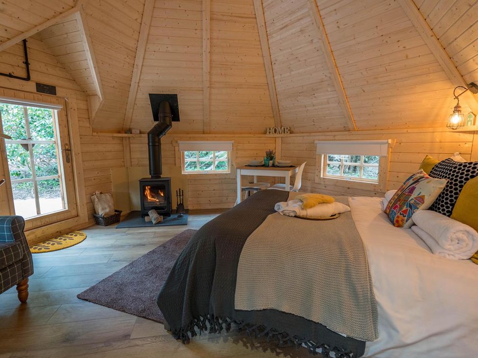 A bedroom with a stove, bed, and table at Punch Tree Cabins Outdoor Bath Wood Burner in Carluke near Larkhall
