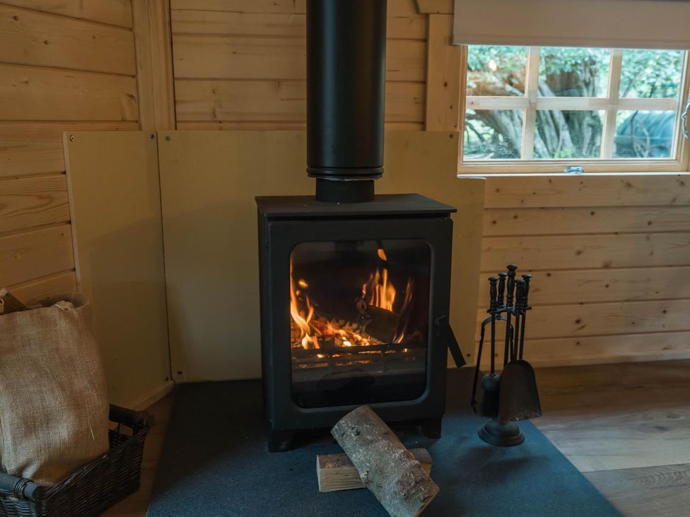 A living room with a wood burner and firewood at Punch Tree Cabins Outdoor Bath Wood Burner Carluke near Larkhall