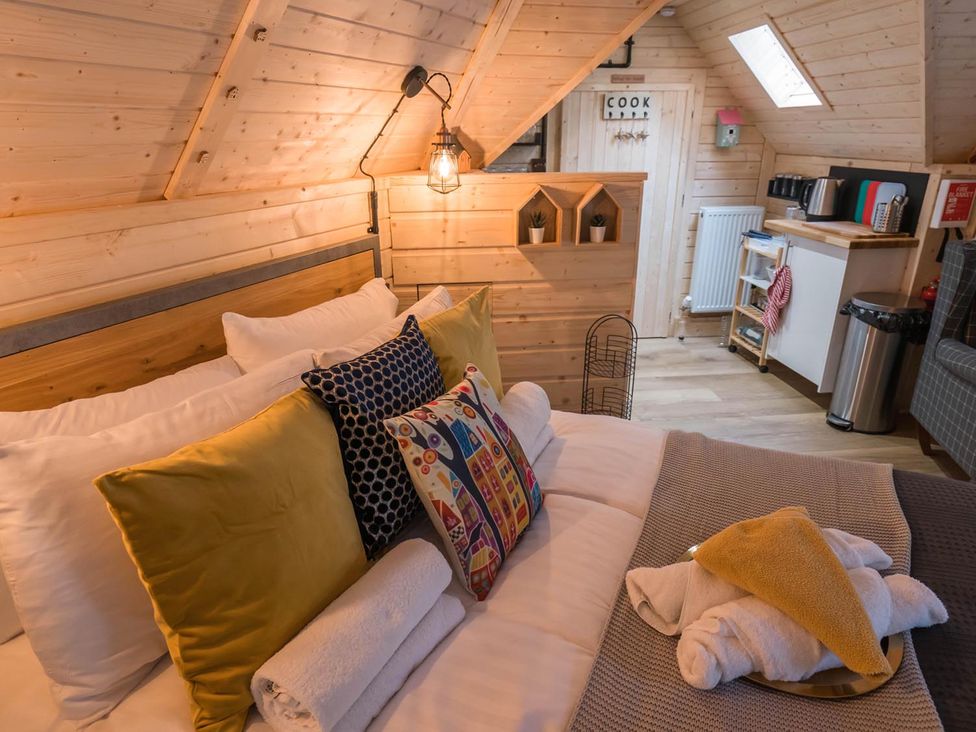 A bedroom with a bed and kitchenette at Punch Tree Cabins Outdoor Bath Wood Burner in Carluke near Larkhall