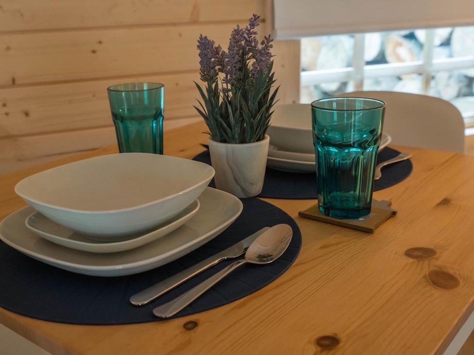 A dining table set with plates and glasses at Punch Tree Cabins Outdoor Bath Wood Burner in Carluke near Larkhall