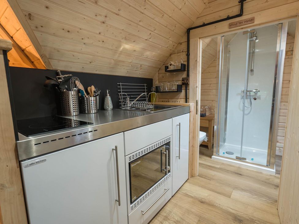 A kitchen area with a stove, oven, sink, and a shower at Punch Tree Cabins Outdoor Bath Wood Burner, Carluke near Larkhall