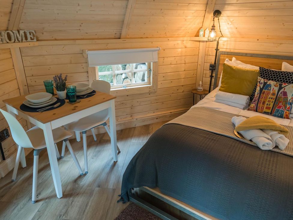 A bedroom with a bed and dining table at Punch Tree Cabins Outdoor Bath Wood Burner in Carluke near Larkhall