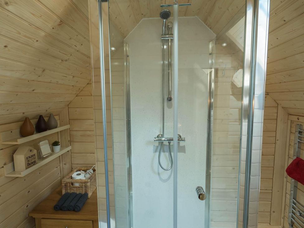 A bathroom featuring a shower, shelf with decorative items at Punch Tree Cabins Outdoor Bath Wood Burner, Carluke near Larkhall