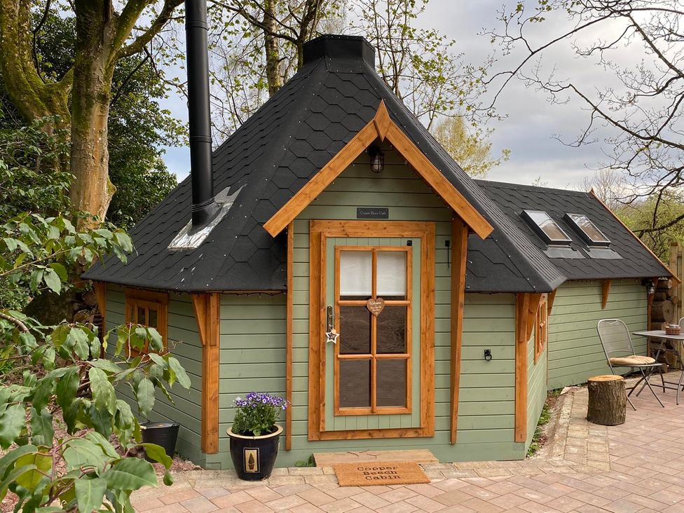 A cabin with a chimney and flower pot at Copper House Cabin in Carluke near Larkhall