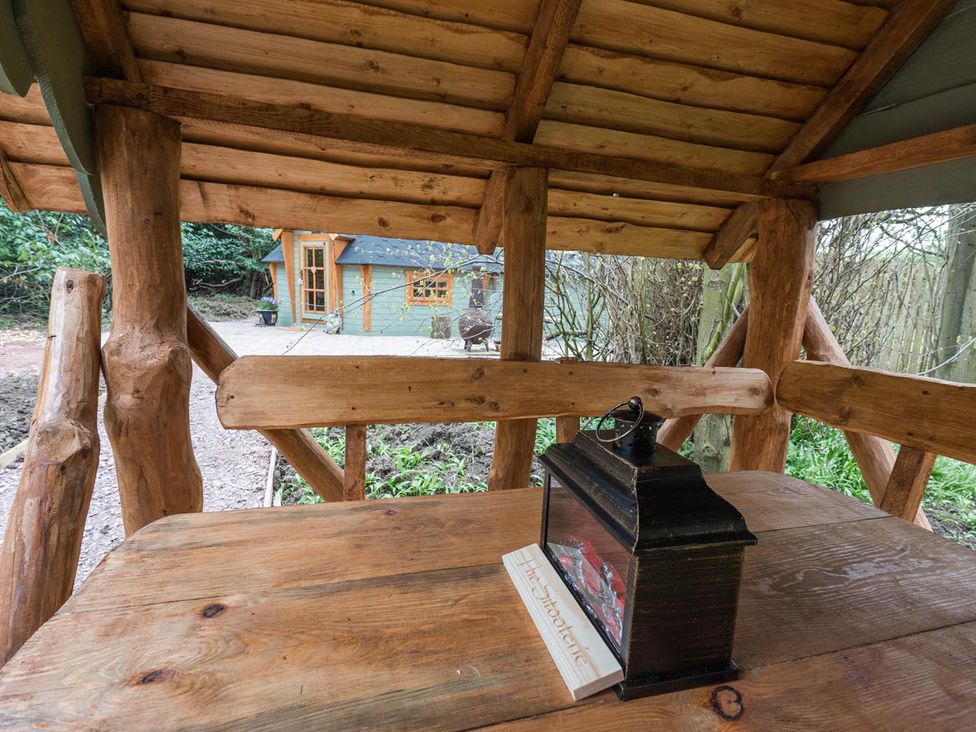 An outdoor seating area with a wooden table and lantern at Punch Tree Cabins Outdoor Bath Wood Burner Carluke near Larkhall