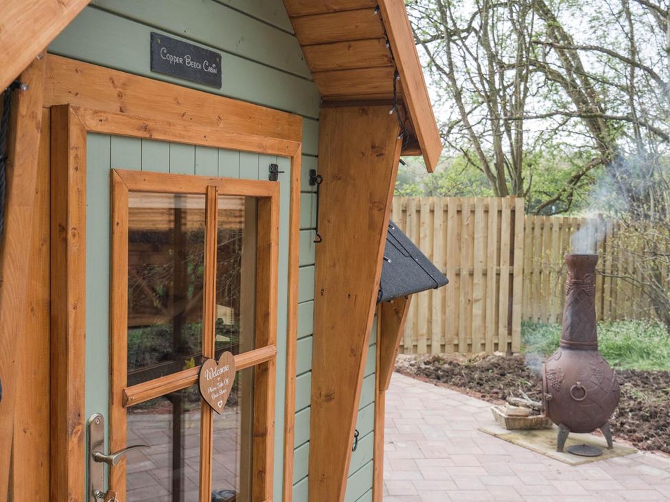 An outdoor view of a cabin door and a chiminea at Copper Beech Cabin near Larkhall