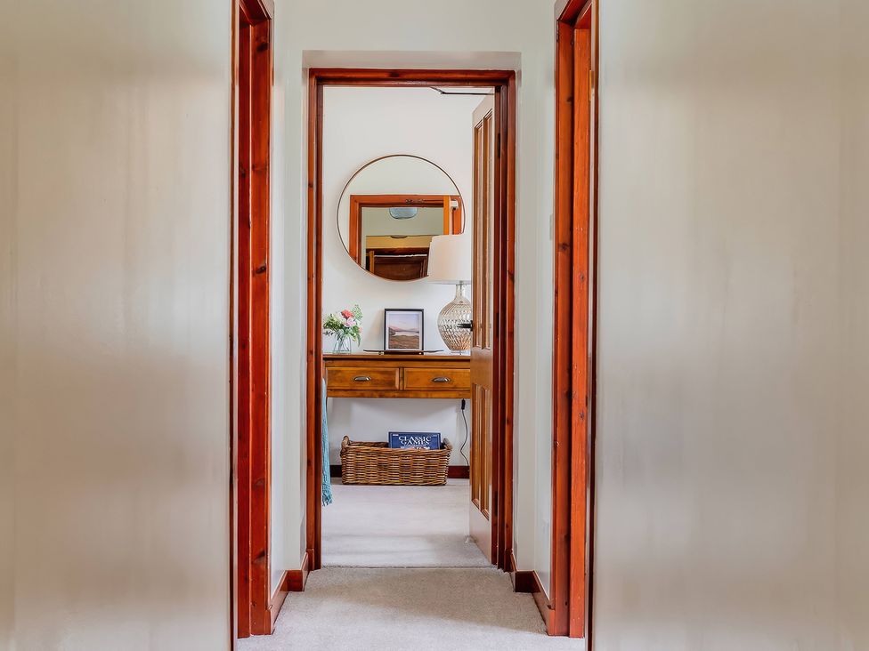 A hallway with a table and lamp at The Old Barn in Lairg