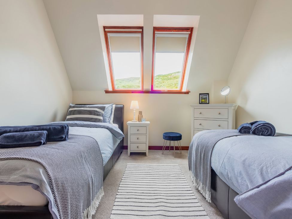 A bedroom with two beds and a desk lamp at The Old Barn in Lairg