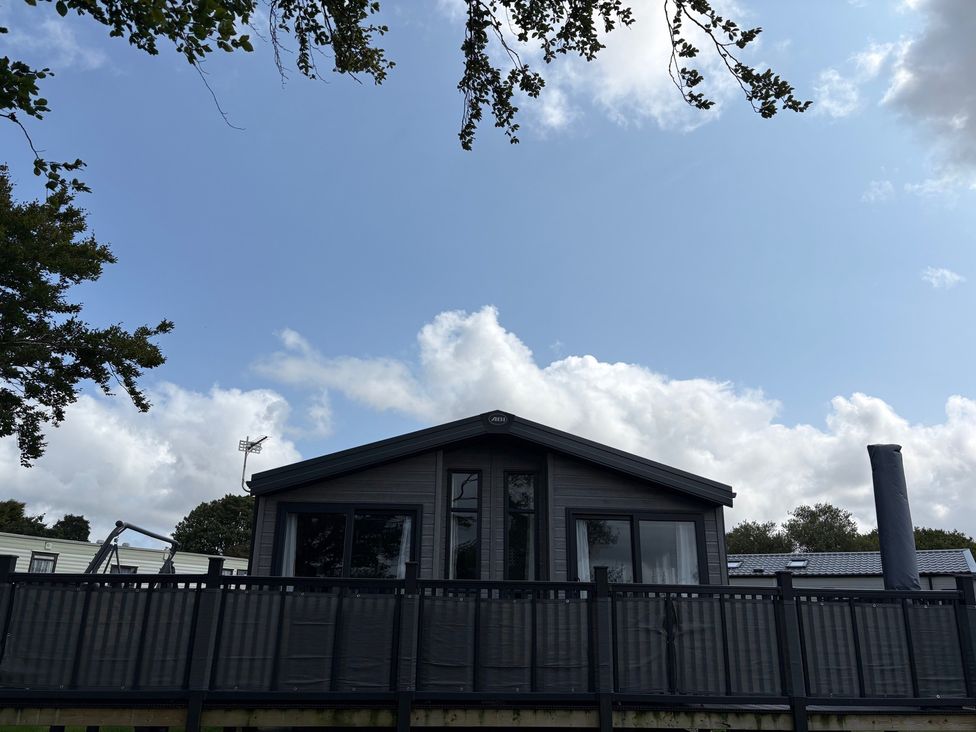 A cabin with decking and chimney at Harrogate Lodge Sleeps4 South Facing Decking Lufflands Caravan Park near Holsworthy