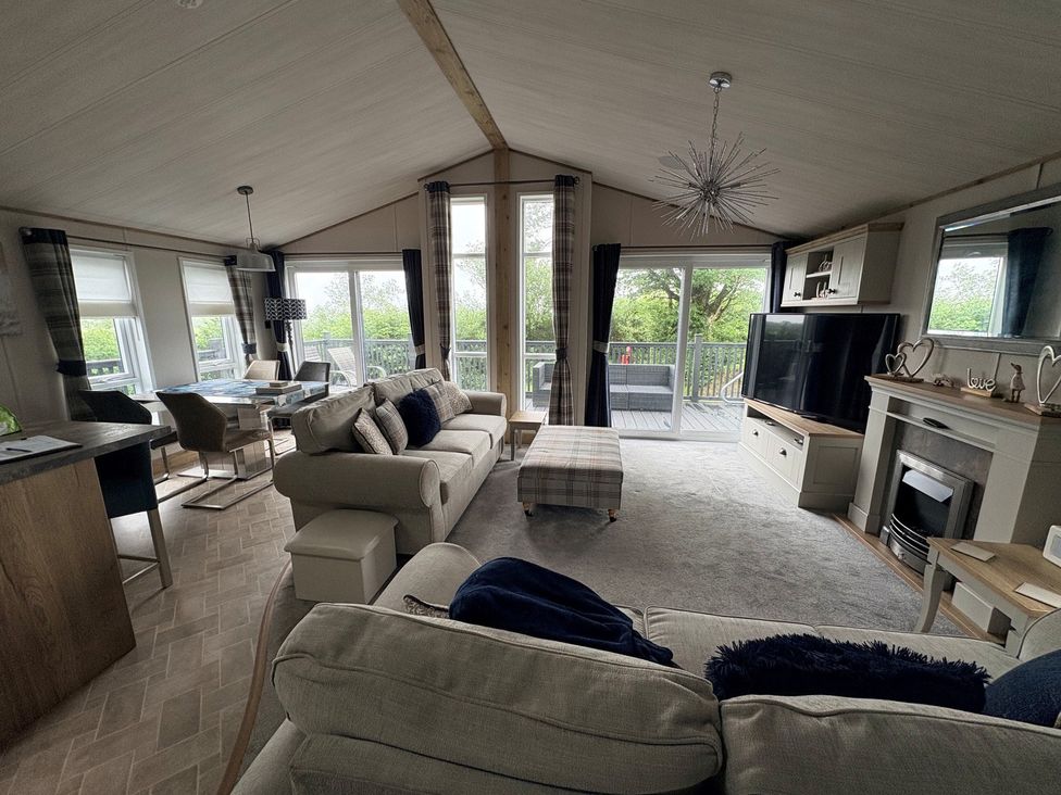 A living room with a sofa and television at Harrogate Lodge Sleeps4 South Facing Decking, Lufflands Caravan Park near Holsworthy