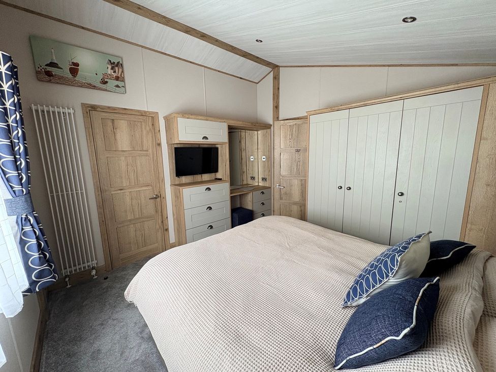 A bedroom with a bed, television, and storage furniture at Harrogate Lodge Sleeps4 South Facing Decking Lufflands Caravan Park near Holsworthy