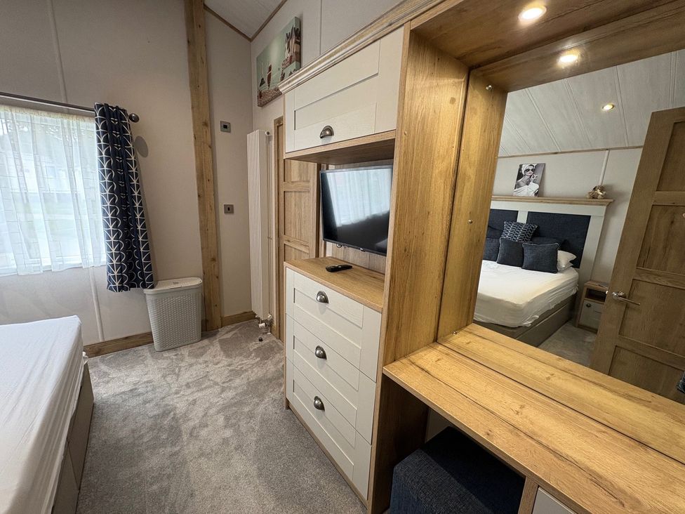 A bedroom with a bed, dresser, and television at Harrogate Lodge Sleeps4 South Facing Decking Lufflands Caravan Park near Holsworthy
