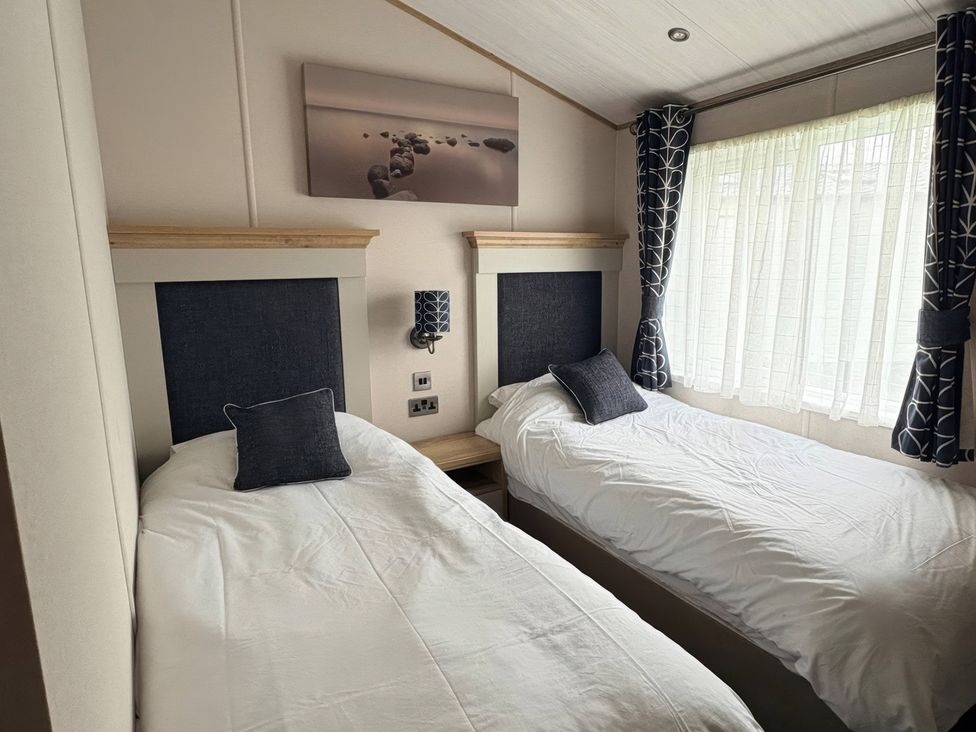 A bedroom with two single beds and a window at Harrogate Lodge Sleeps4 South Facing Decking Lufflands Caravan Park near Holsworthy