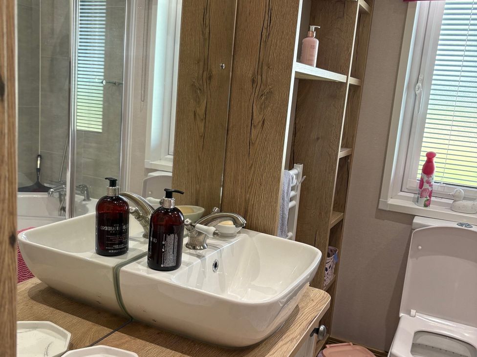 A bathroom with a sink and shelf at Harrogate Lodge Sleeps4 South Facing Decking near Lufflands Caravan Park near Holsworthy