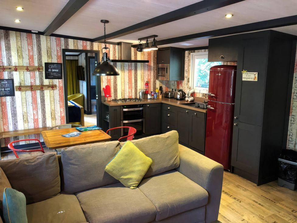 A living room with a kitchen area and a sofa at Sandy Balls Holiday Park Pet Friendly Lodge in Godshill, Hampshire