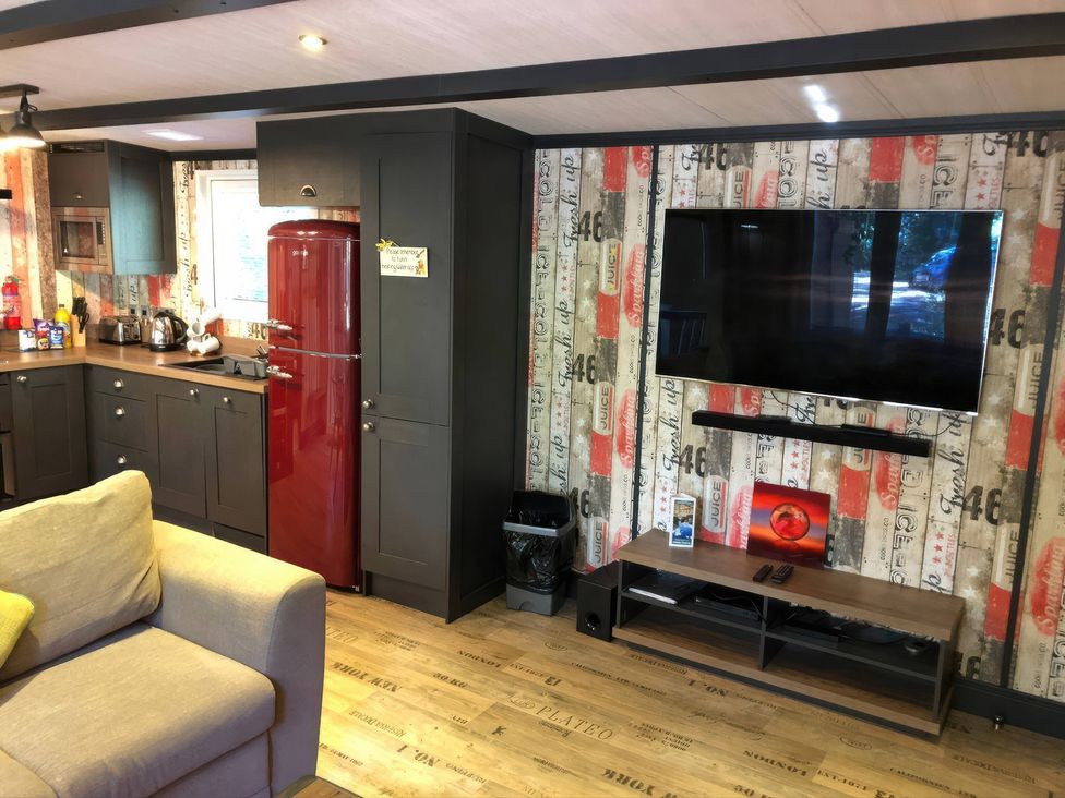 A kitchen with a red refrigerator and a television at Sandy Balls Holiday Park Pet Friendly Lodge, Godshill, Hampshire