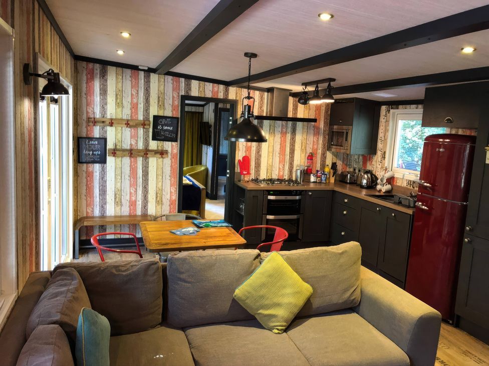 A kitchen with dining table and red refrigerator at Sandy Balls Holiday Park Pet Friendly Lodge in Godshill, Hampshire