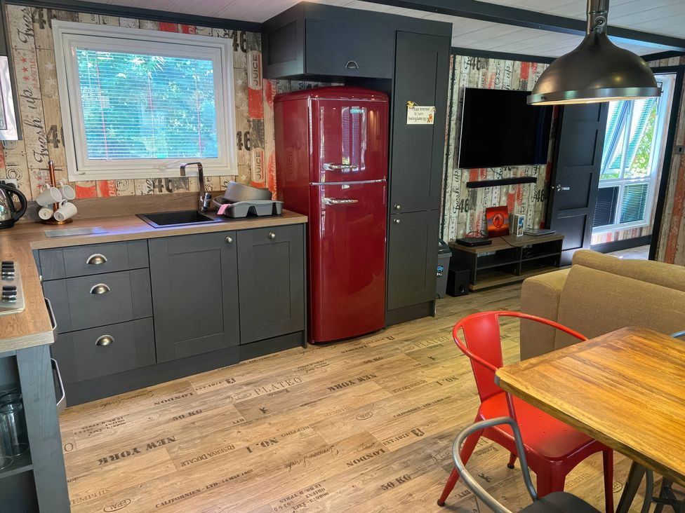 A kitchen with a refrigerator and a dining table at Sandy Balls Holiday Park Pet Friendly Lodge in Godshill, Hampshire