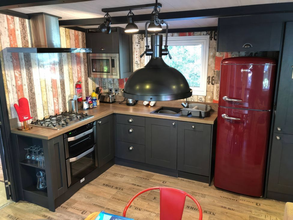 A kitchen with appliances and cabinets at Sandy Balls Holiday Park Pet Friendly Lodge in Godshill, Hampshire