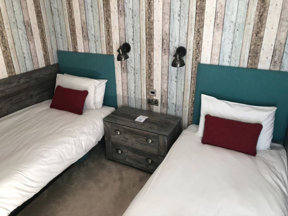 A bedroom with two single beds and a nightstand at Sandy Balls Holiday Park Pet Friendly Lodge in Godshill, Hampshire