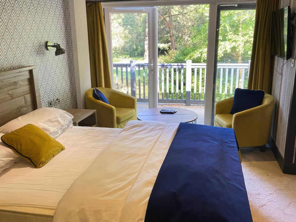 A bedroom with a bed and chairs at Sandy Balls Holiday Park Pet Friendly Lodge in Godshill, Hampshire