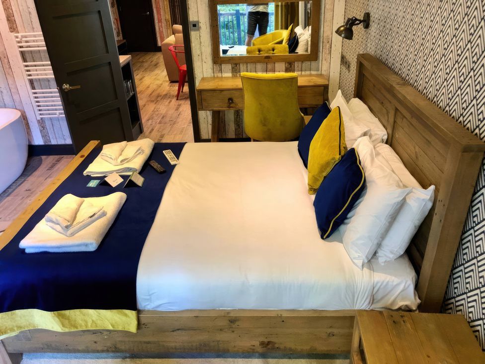 A bedroom with a bed, chair, and mirror at Sandy Balls Holiday Park Pet Friendly Lodge Godshill, Hampshire