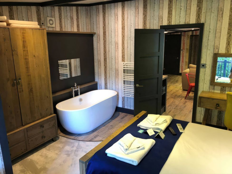 A bathroom with a bathtub and wardrobe at Sandy Balls Holiday Park Pet Friendly Lodge in Godshill, Hampshire