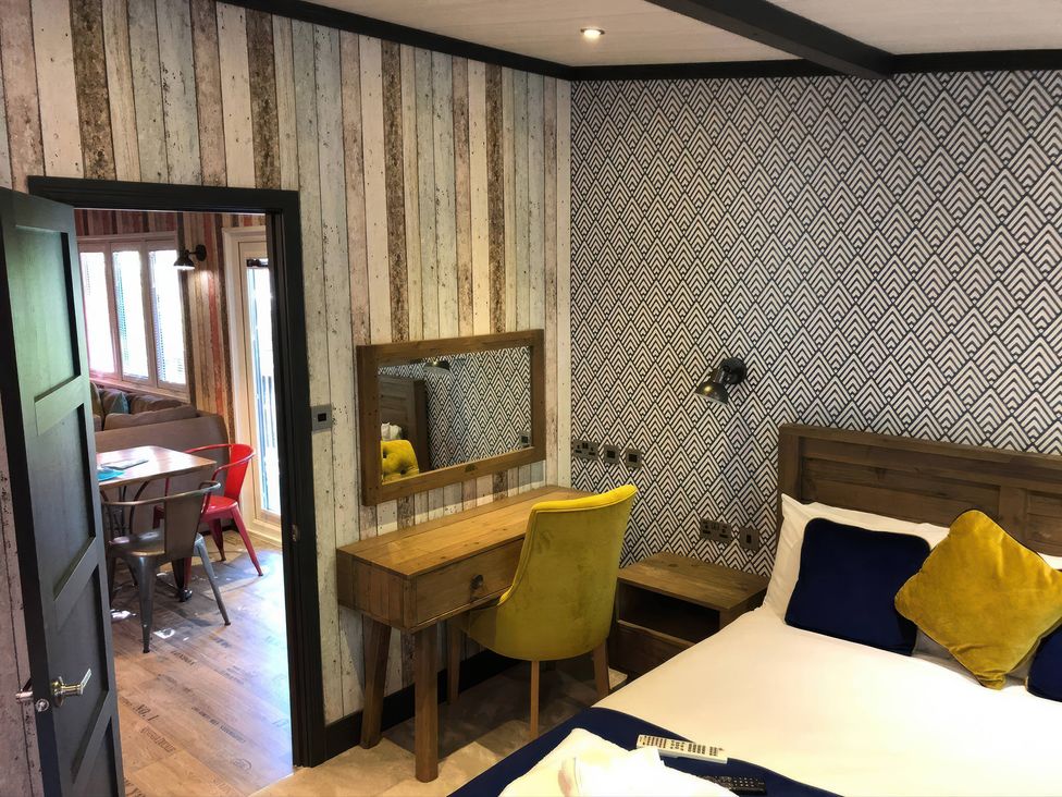 A bedroom with a bed, mirror and desk at Sandy Balls Holiday Park Pet Friendly Lodge in Godshill, Hampshire
