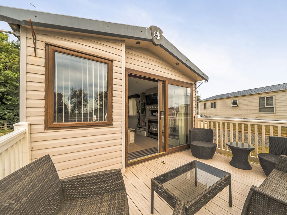 An outdoor area with decking and wicker furniture at The Lodge in Tunstall, North Yorkshire