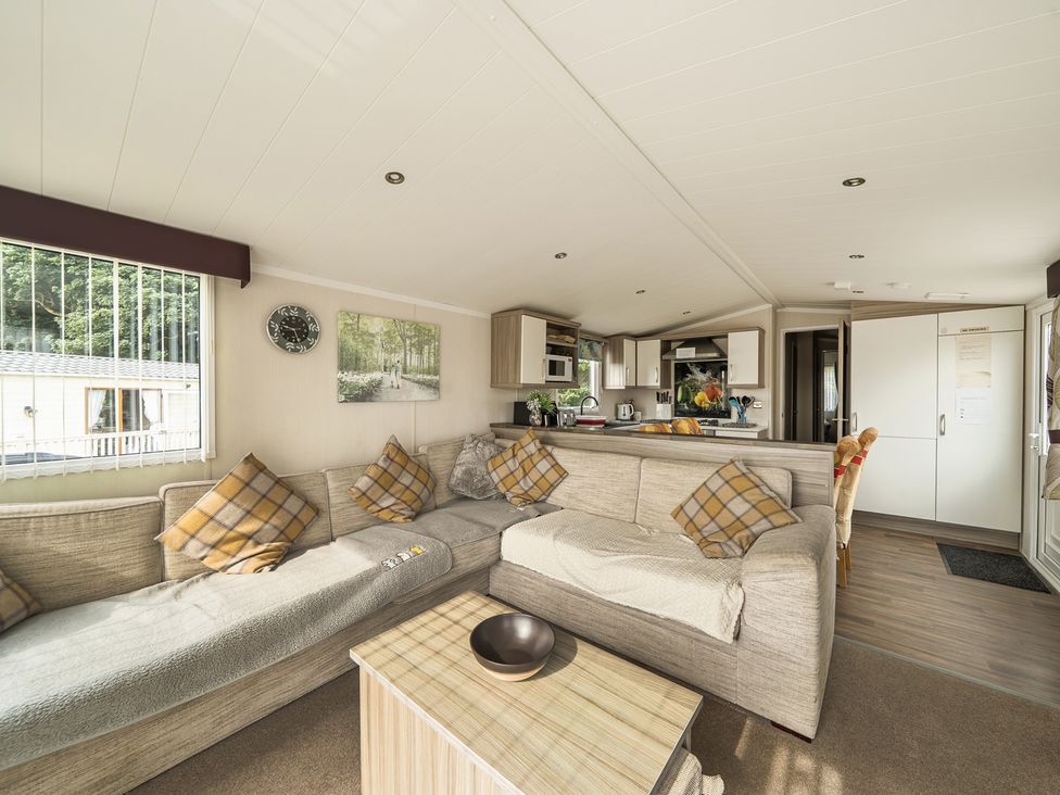 A living room with a sofa and kitchen area at a property in Tunstall, North Yorkshire