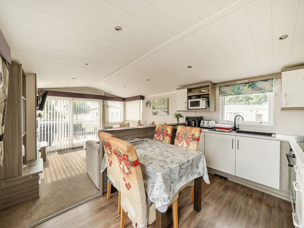 A living room with a dining table and kitchenette at a property in Tunstall, North Yorkshire