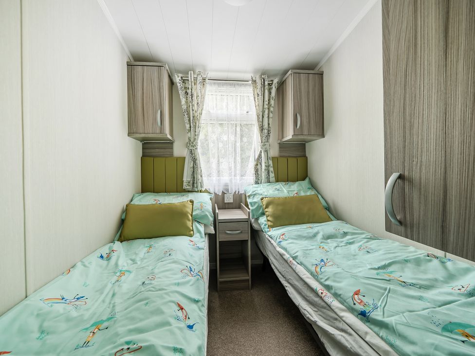 A bedroom with two beds and a window at The Old Barn in Tunstall, North Yorkshire