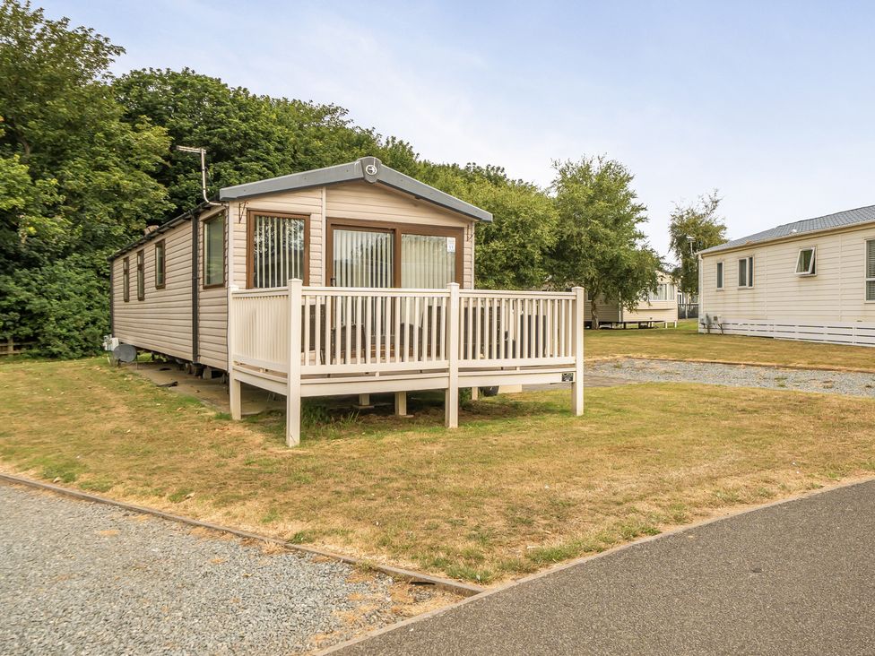 A mobile home with a deck in an outdoor area at Tunstall, North Yorkshire