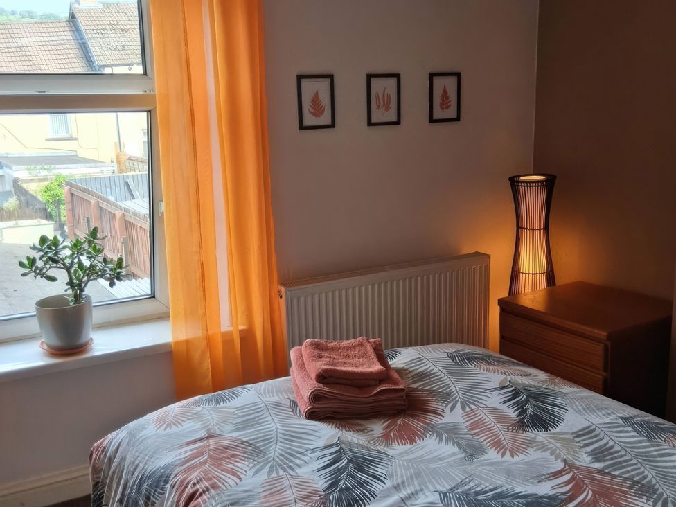 A bedroom with a bed, towels, a lamp, and a window at The Old Barn in Newbridge, Caerffili
