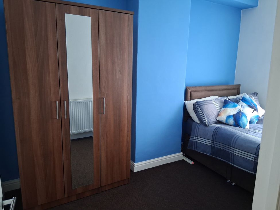 A bedroom with a bed and wardrobe at The Old Barn in Newbridge, Caerffili