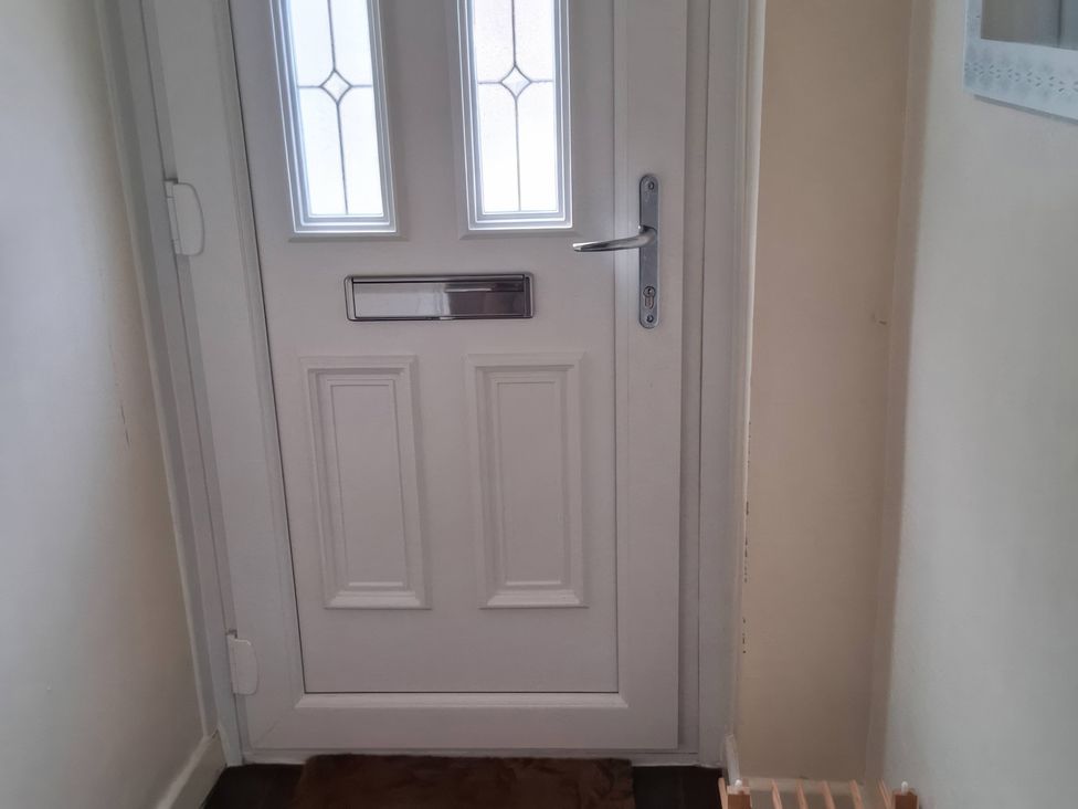 A hallway with a white door and doormat at a property in Newbridge, Caerffili