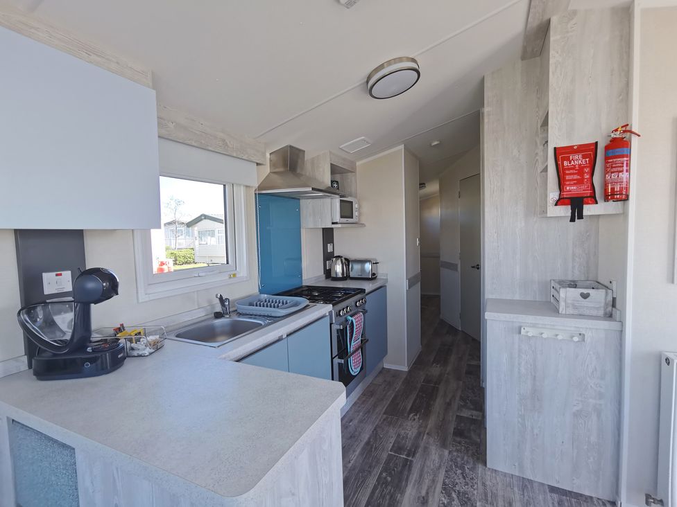 A kitchen with sink, cabinets, stove and microwave at 