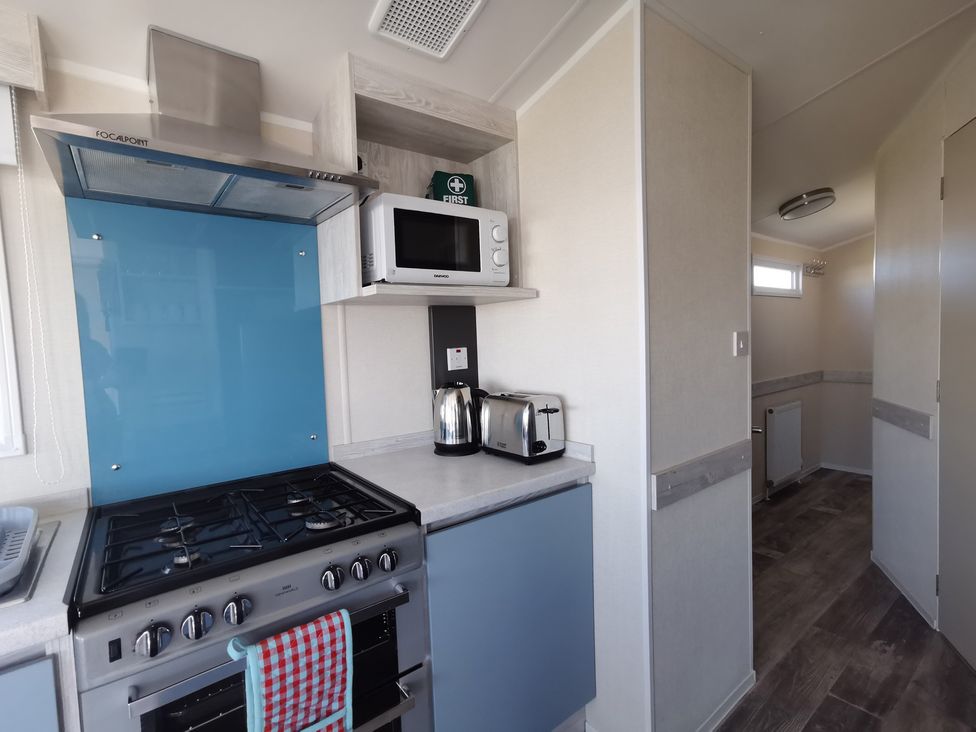 A kitchen with a gas stove, microwave, and kettle at the property