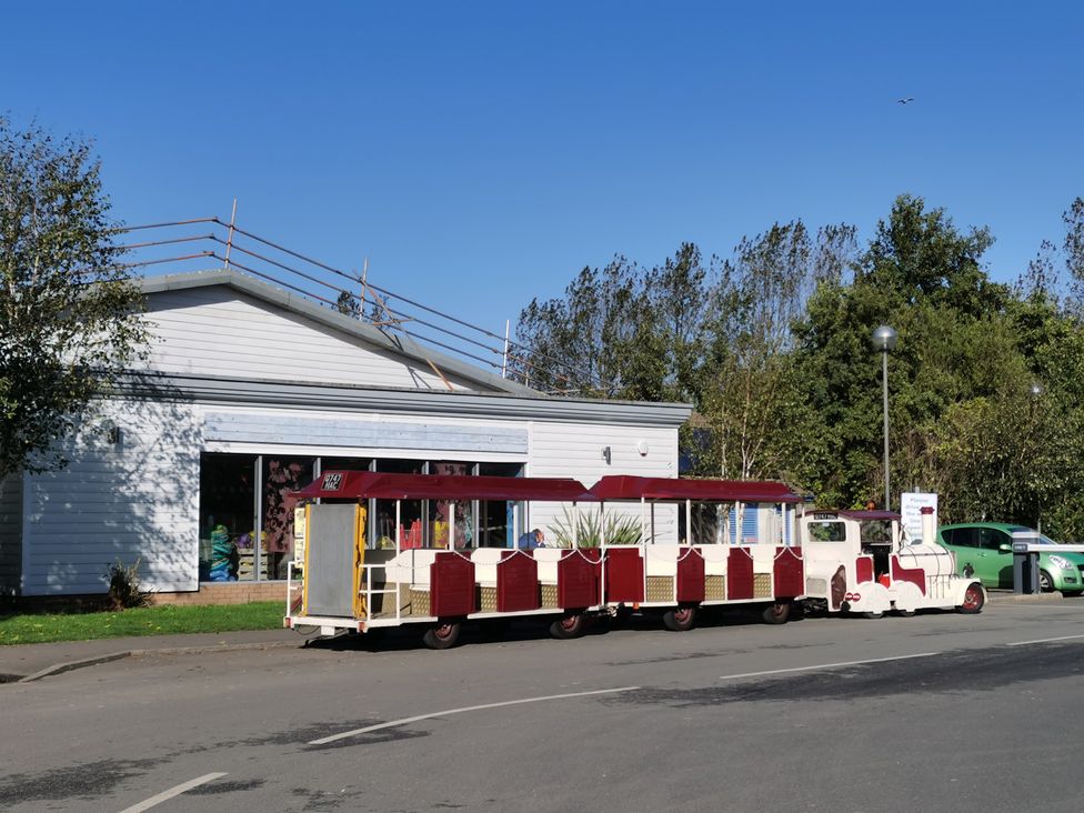 A train near a building with trees on the side at 