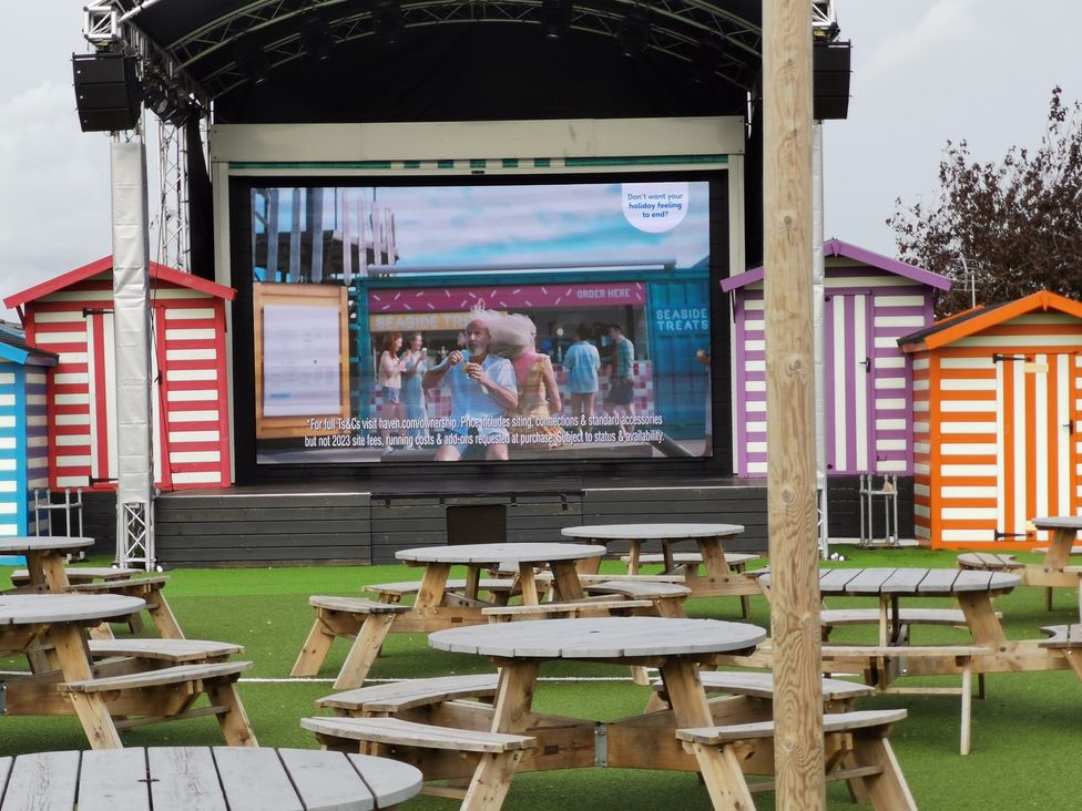 An outdoor space with tables and a large screen at a coastal venue