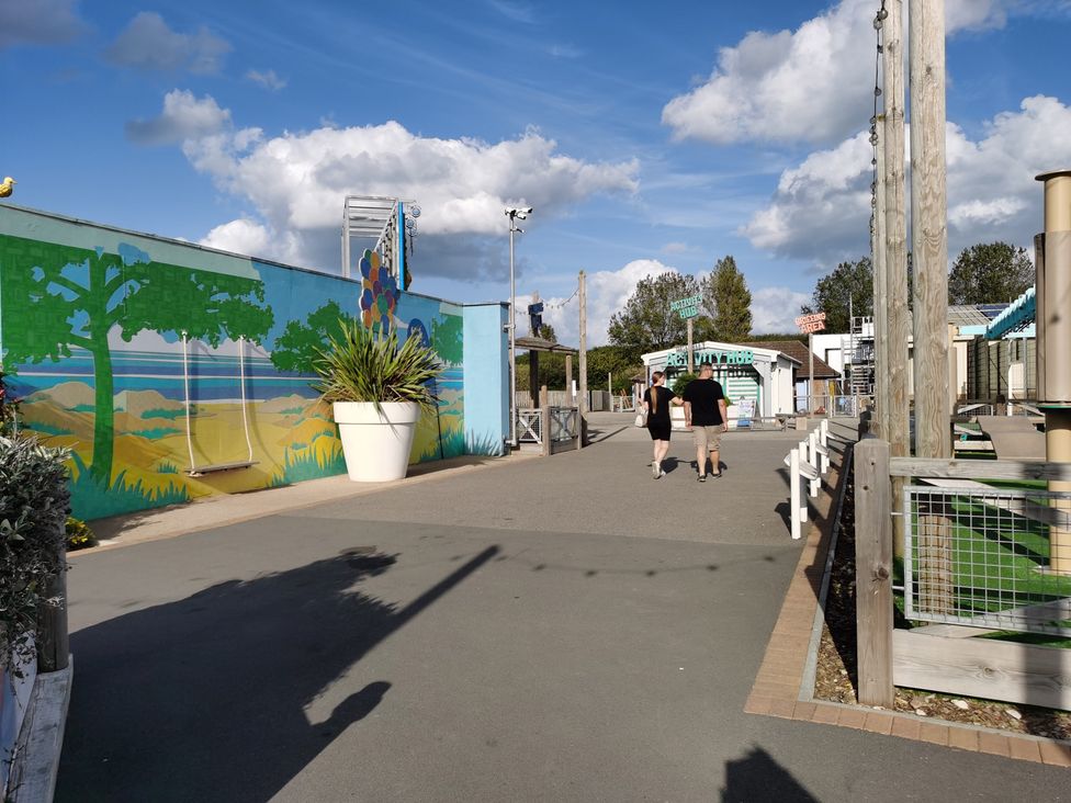 An outdoor area with a mural and two people walking at the amusement park