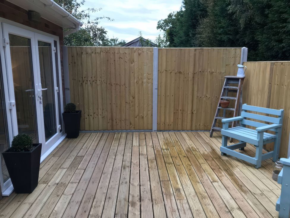 An outdoor space with decking, a fence and a chair at Oakley Country Retreat1 Bed Garden Free Parking, Nantwich