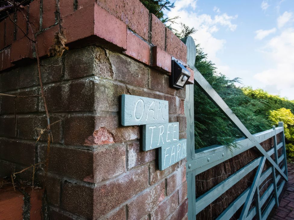 A brick wall with a gate and sign at Oak Tree Farm Nantwich