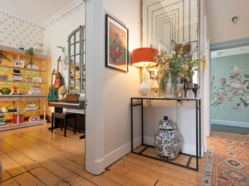A hallway with a bookshelf, piano, and decorative vase at the property in 
